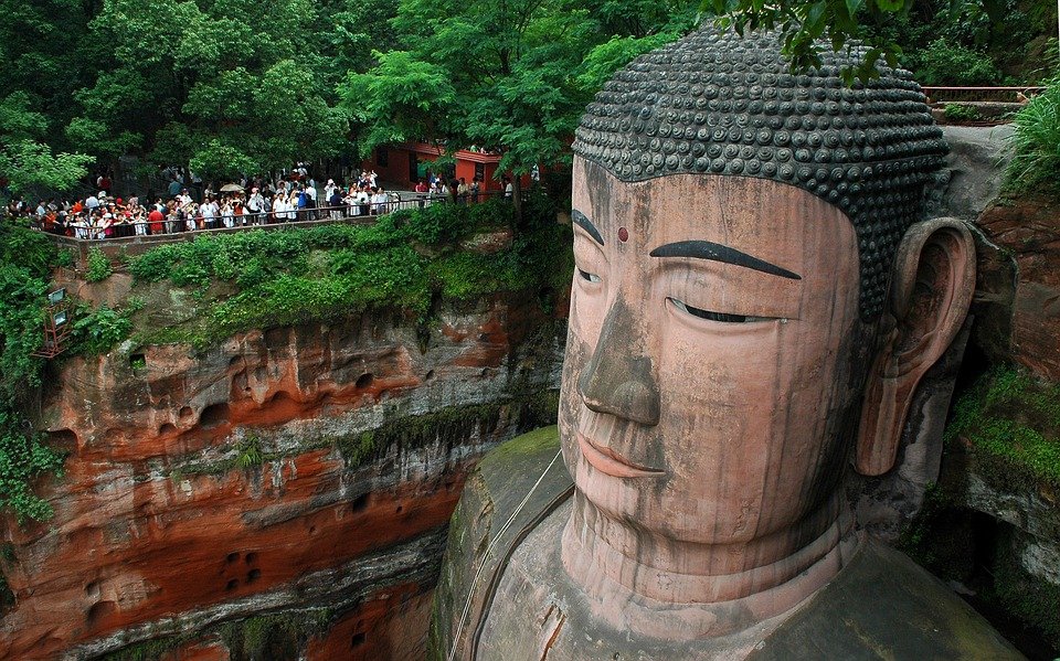 estatua gigante de um buda sendo admirada por inumeros turistas