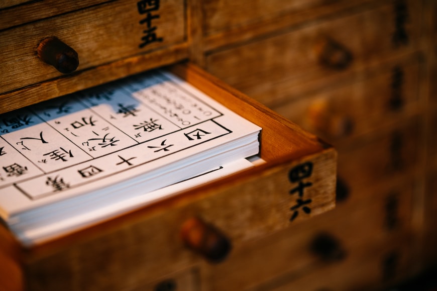 gaveta aberta de madeira contendo vários papéis com ideogramas chineses