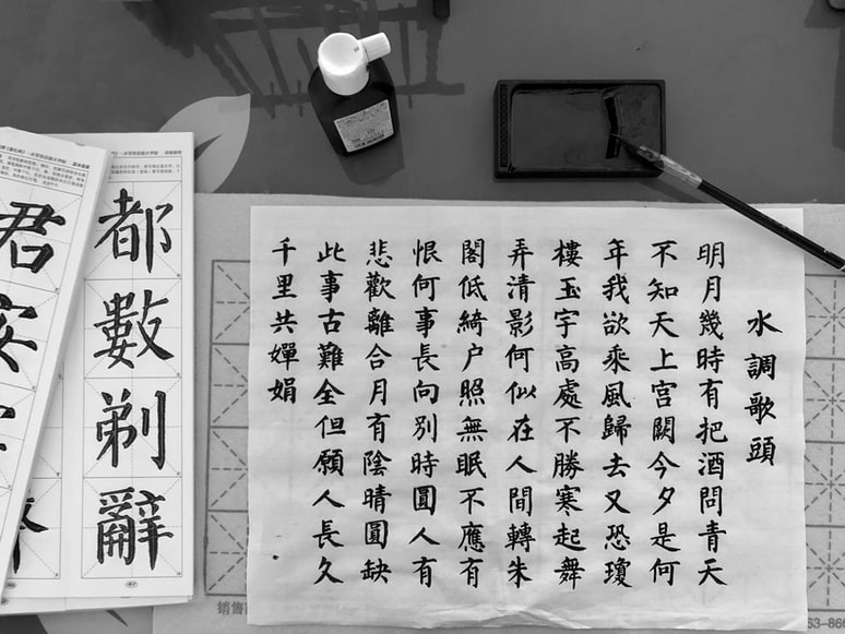 foto em preto e branco com ideogramas chineses escritos em uma folha de papel